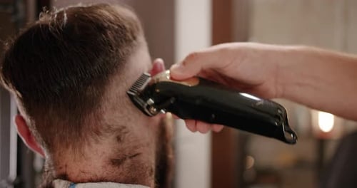 Hübscher Mann bekommt neue Frisur mit elektrischem Trimmer Nahaufnahme mit Trimmer