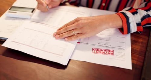 Person Fills Out Financial Paperwork at Desk