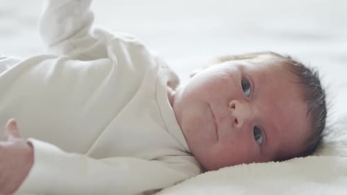 Blue Eyed Infant Lying Awake on Blanket