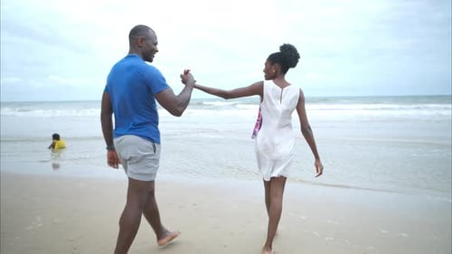 Happy couple enjoying a playful walk on the beach, laughing and holding hands