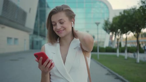 Attractive Young Woman Listening to Music in Headphone Use Smartphone at City Walk Sunset Look