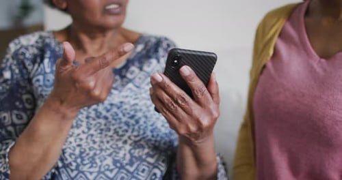 Senior Woman and Young Adult Looking at Smartphone
