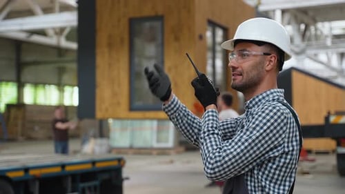 Foreman with Walkie Talkie Manages the Loading of a Prefabricated Modular House to Truck