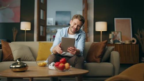 Man Using Tablet for Video Call on Sofa