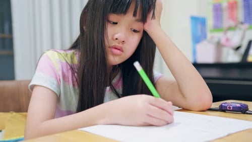 Asiatisches junges Mädchen, das am Wochenende Hausaufgaben im heimischen Wohnzimmer macht.