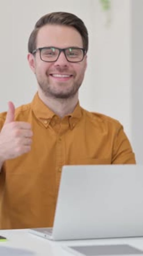 Man Smiling and Giving Thumbs Up at Computer