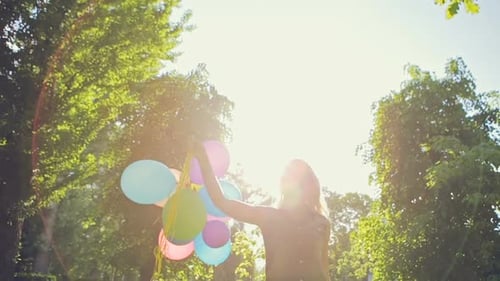 Woman with Balloons in Green Park on Sunny Day