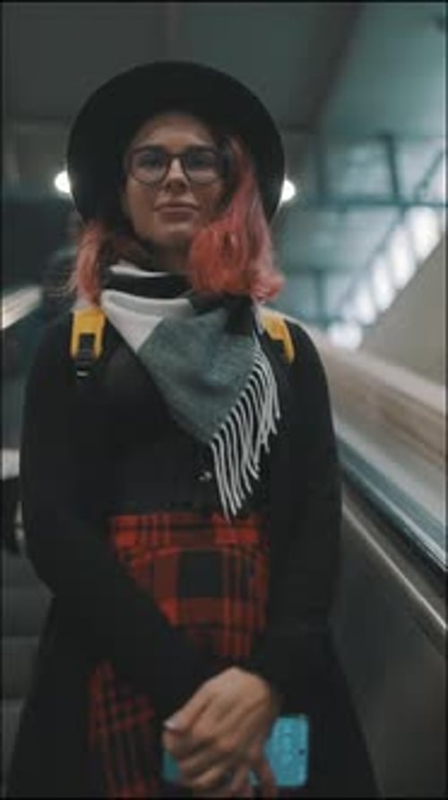 Woman Rides Escalator in Urban Setting with Backpack