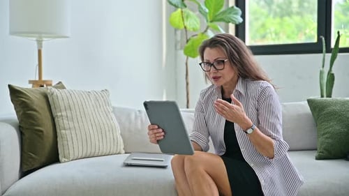 Woman Using Tablet On Sofa In Bright Home