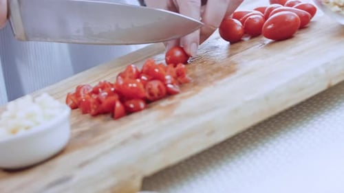 Hands Slicing Cherry Tomatoes on Cutting Board