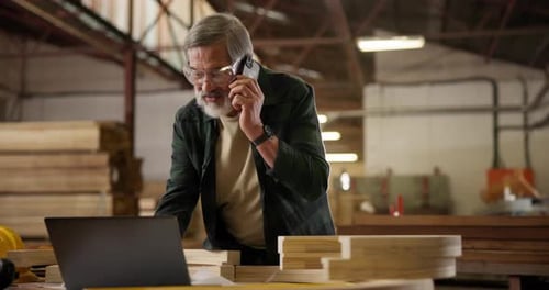 Carpenter, laptop and phone call in workshop for business, deal or manufacturing negotiation