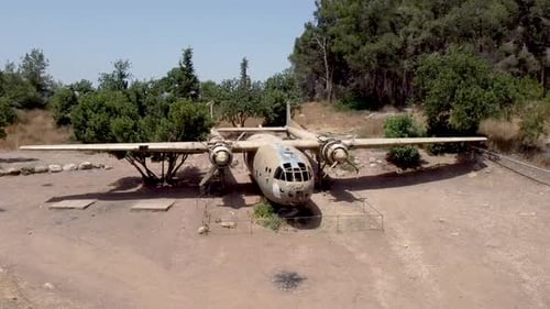 aerial turning and rising drone shot of an old dismantled army plane monument placed on an empty dir