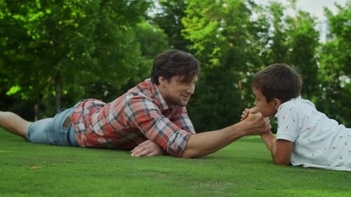 Closeup Father and Son Lying on Green Grass in Field. Smiling Man