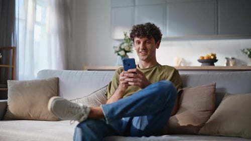 Man Relaxing on Couch Using Smartphone