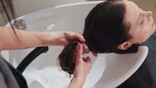 Relaxing Hair Wash Session Stylist Carefully Massages Shampoo Into Wet Hair Serene Scene of Woman