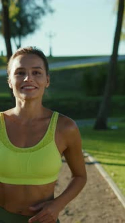Une jeune femme énergique faisant du jogging dans un équipement d'entraînement lumineux et coloré dans un environnement de parc