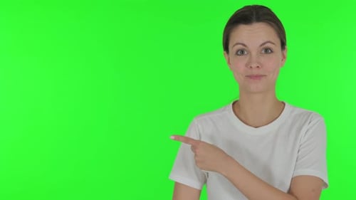 Portrait of Pointing Young Woman Showing Copyspace on Green Background
