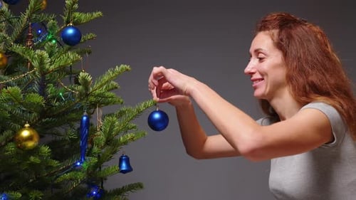 Woman Decorating Christmas Tree with Blue Ornaments