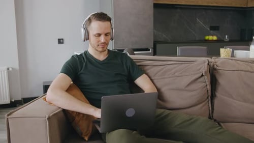Man working on laptop at home with headphones