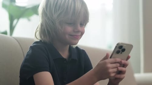 Young Boy Using Phone on Couch at Home