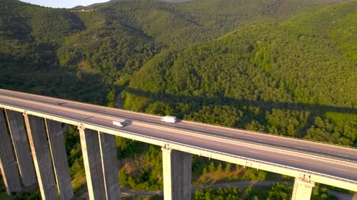 Aerial Drone View of Cars Passing Highway Bridge in the Mountains at Sunset
