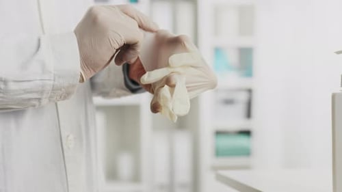 Doctor. A male specialist in special clothing puts on medical gloves in the office. Close-up clinic