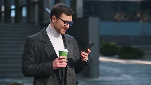 Man With Coffee Using Smartphone in Urban Setting