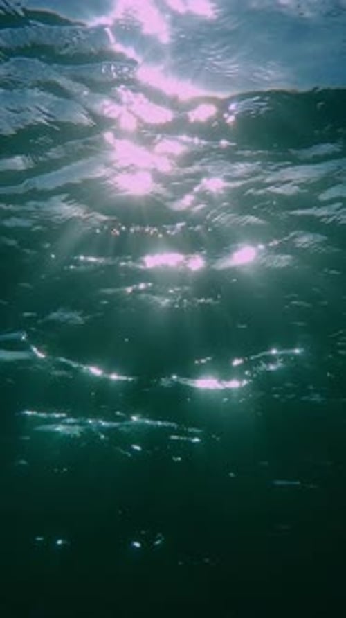 Unterwasser-Sonnenlicht scheint unter tiefem Wasser mit Wellen auf der Wellenoberfläche