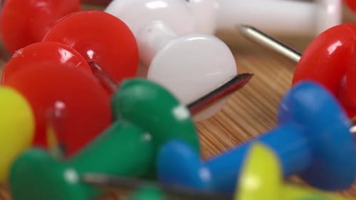 Colorful push pins rotating on the table macro. Drawing pins for marking on the map of the Earth