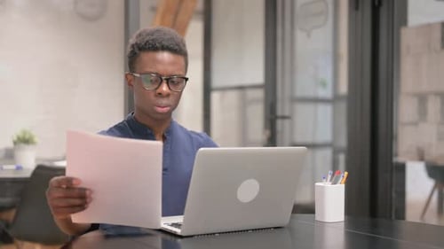 Adult Reading Documents While Working at Laptop