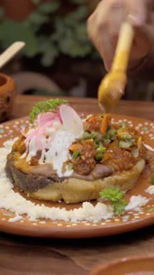 Adicionando molho vermelho picante ao prato tradicional mexicano com colher de pau