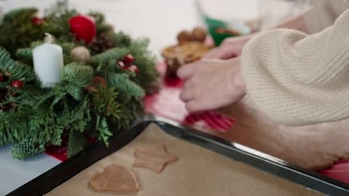 Hands Placing Gingerbread Cookies on Baking Sheet