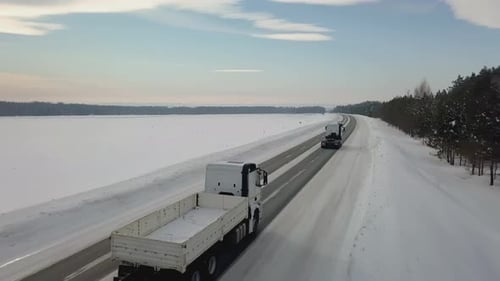 Blick von oben auf die Winterstraße, auf der Autos und Lastwagen fahren