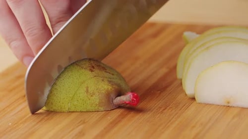 Chef Cuts Bio Green Pear with Knife on a Cutting Board to Make Dessert Compote or Fruit Juice