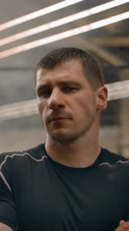 Muscular Man Stands with Arms Crossed in Modern Gym