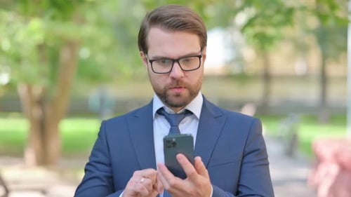 Man Celebrates Positive News on Phone in Park