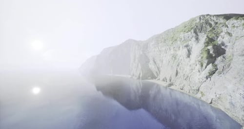Foggy Coastal View Revealing Rocky Cliffs and Calm Water at Dawn