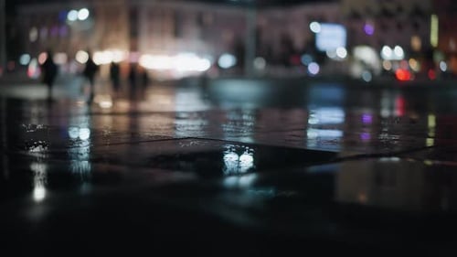 Nighttime City Street with Blurred Reflections and Pedestrians