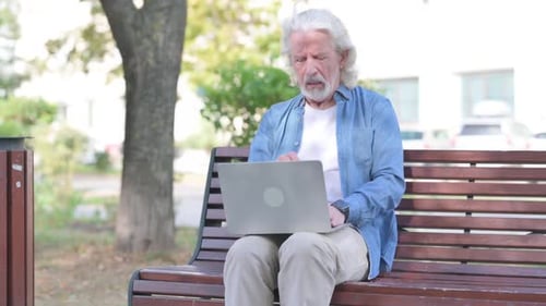 Senior Man Using Laptop on Park Bench