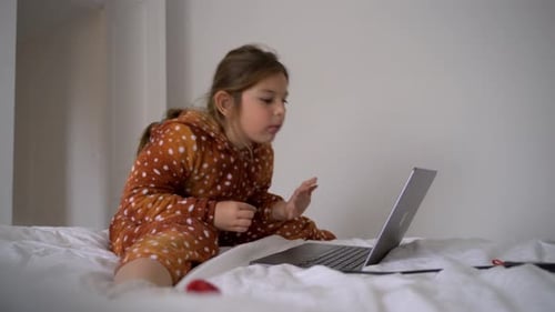 Child Using Laptop While Sitting on Bed