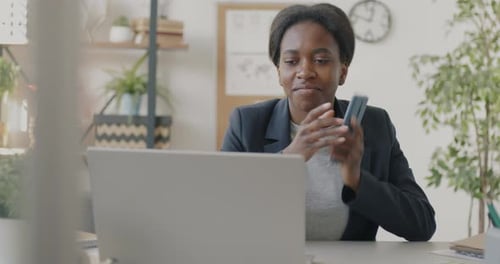 Businesswoman Typing with Laptop and Discussing Work on Mobile Phone in Office