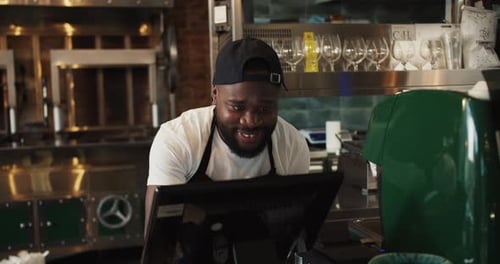 A Black Person Works Dancing in a Doner Market Against the Backdrop of a Barbecue A Man in a Black