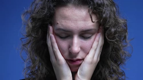 Sad pensive woman close-up face with hands supporting cheeks, thoughtful melancholic