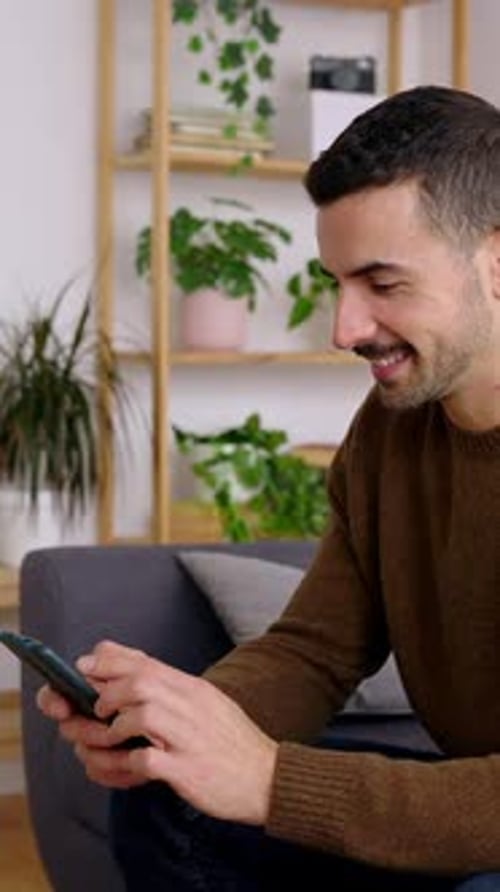 Man Sitting on Couch Using Smartphone