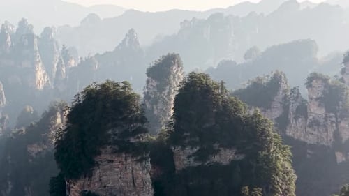 Iconic solitary rock pillar with trees on top surrounded by Zhangjiajie Avatar mountains, China,