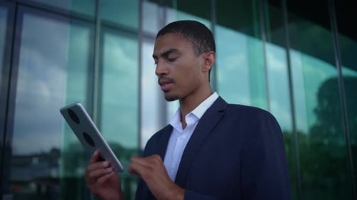 A Business Professional Confidently Using a Tablet While Standing Outside a Modern Building
