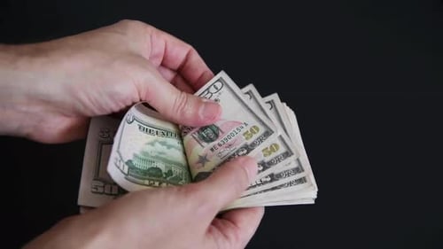 Hands Counting Stack of United States Fifty Dollar Bills