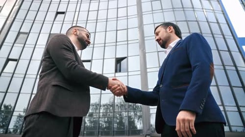 Two Smiling Business Male Colleagues Greeting Each Other Shaking Hands Outdoor Downtown Skyscraper