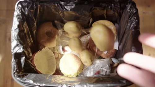 Food Waste Discarded into a Black Trash Can