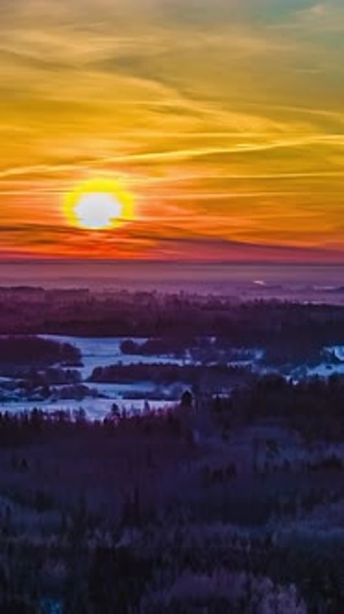 Drone en hyperlapsus du soleil s'élevant au-dessus de l'horizon, projetant une lueur chaude sur une épaisse couche de neige et silencieux